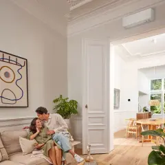 Pareja feliz en un salón moderno. El aire acondicionado Daikin, símbolo de calor confortable, se ve en la pared.