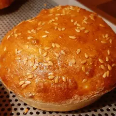 Un pain à burger maison doré et moelleux, parsemé de graines de sésame.