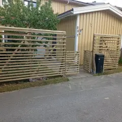 Nya trästaket byggs för att bygga insynsskydd vid ett gult hus.
