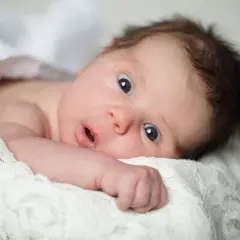 Un neonato con occhi spalancati, che sembra scoprire il mondo. La sua espressione curiosa cattura il momento in cui iniziano a vedere i neonati.