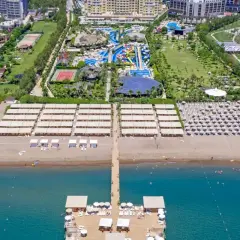 Widok z lotu ptaka na rozległy royal holiday palace z basenami, zjeżdżalniami, kortami tenisowymi i plażą z leżakami.