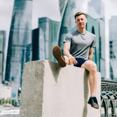 Mężczyzna w sportowym stroju siedzi na kamiennym postumencie, w tle nowoczesne wieżowce. Czasem czuję, że nie mogę złapać oddechu podczas biegania.