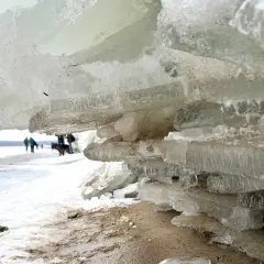 Mikoszewo: lodowe góry na plaży, ludzie i pies spacerują po zamarzniętym morzu.