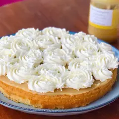 Tårta med fluffig grädde och en gyllene botten, troligen med smak av lemon curd. En burk syns i bakgrunden.