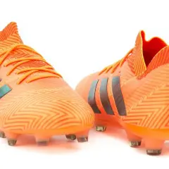 Pomarańczowe buty piłkarskie adidas Nemeziz 18.1 z czarnymi paskami i wzorem zygzak.