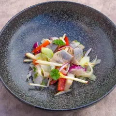 Heringssalat Hausfrauenart: ein deftiger Salat mit Hering, Apfel, Zwiebeln und Paprika in einer dunklen Schüssel.
