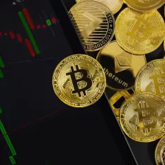 Złote monety kryptowalut obok wykresu świecowego. Dowiedz się, jak rozliczać kryptowaluty, analizując dane rynkowe.