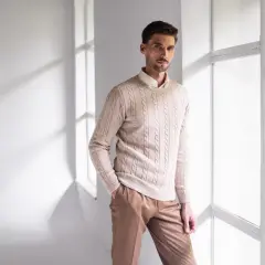 Elegancki strój na sylwestra męski: beżowy sweter z warkoczami i brązowe spodnie. Idealny na imprezę.