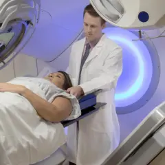 Pacjentka leży na stole terapeutycznym, a lekarz nadzoruje proces radiochemioterapii. To nowoczesna metoda leczenia nowotworów.