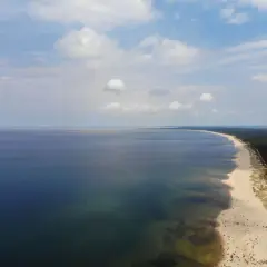 Szeroka, piaszczysta sobieszewo plaża z mnóstwem ludzi wypoczywających nad spokojnym morzem.