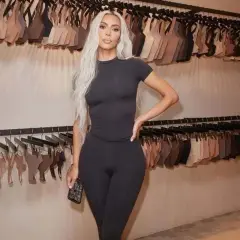 Kim Kardashian w czarnym dopasowanym stroju, na tle wieszaków z bielizną. Skims w Polsce gdzie kupić? Sprawdź ofertę!
