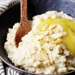Reisflocken, cremig gekocht, mit Apfelmus und Mandelblättchen bestreut. Ein leckeres Frühstück, das zeigt, was Reisflocken sind.