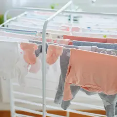 Suszenie ubranek dla noworodka na suszarce. Czy trzeba prasować ubranka dla noworodka? Delikatne body i skarpetki schną, czekając na maluszka.
