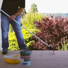 Application d'un saturateur sur une terrasse en bois. Le rouleau est en action pour un nettoyage et une protection parfaits.