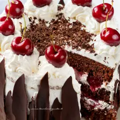 Una fetta di foresta nera torta, con panna montata, ciliegie e scaglie di cioccolato.