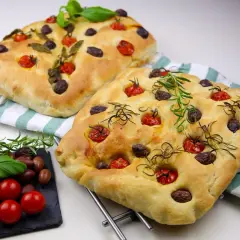Två gyllene focaccia med tomater, oliver och rosmarin. Ett perfekt focaccia recept från Zeina som ser ljuvligt ut!