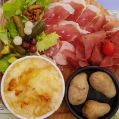Assiette généreuse de charcuterie, fromage gratiné, pommes de terre et crudités, un vrai plat savoyard pour les gourmands.