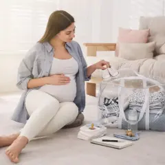 Przyszła mama przygotowuje torbę do porodu, układając maleńkie buciki na wierzchu.
