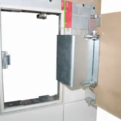 Otwarta, metalowa rama z drzwiczkami rewizyjnymi 60x60, zamontowana w ścianie z płyt gipsowo-kartonowych i płytek.