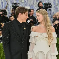 Desiré Inglander och hennes partner ler mot varandra omgivna av fotografer.
