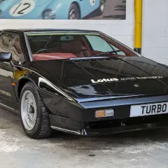 Czarny Lotus Esprit Turbo z czerwonym wnętrzem, z napisem "Lotus ACTIVE SUSPENSION" na masce.