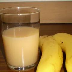 Szklanka orzeźwiającego soku z banana obok dwóch dojrzałych bananów. Idealny napój na szybkie śniadanie.
