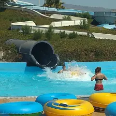 ¡Diversión en el parque Mario Park! Niños se deslizan por toboganes acuáticos y chapotean en la piscina con flotadores coloridos.