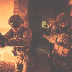 Żołnierze w taktycznym kamuflażu, z bronią w rękach, ćwiczą **CQB co to** jest walka w bliskim kontakcie w ciasnych pomieszczeniach.