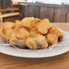Plato de cazon en adobo, trozos de pescado frito y dorado, servido con una rodaja de limón.