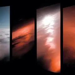 Quattro pannelli verticali mostrano un cielo che sfuma dal blu al giallo e rosso, con nuvole che cambiano colore.