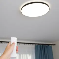 Mano con control remoto ajustando las lámparas led techo.