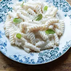 Fusilli conditi con una cremosa salsa alla ricotta, guarniti con foglie di menta fresca. Un piatto semplice e gustoso.