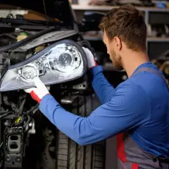 Mécanicien ajustant un phare sur une voiture, résolvant un feu en panne.