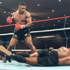 Mike Tyson står över en liggande motståndare i ringen. Hans imponerande fysik visar varför mike tyson vikt var så avgörande.