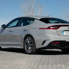 Kia Stinger GT CV gris, visto desde atrás, aparcado sobre adoquines grises.