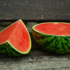 Kawałek i połówka arbuza na drewnianej ławce. Czy pies może jeść arbuza? Tak, ale bez pestek i skórki.