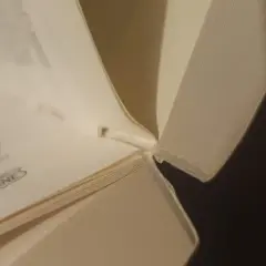 Zbliżenie na grzbiet otwartej książki, pokazujące miejsce, gdzie można zastosować klej, by jak skleić grzbiet książki.
