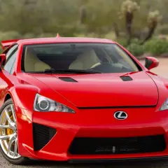 Czerwony Lexus LFA z żółtymi zaciskami hamulcowymi, zaparkowany na tle pustynnego krajobrazu.