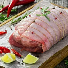 Surowa rolada z indyka, związana sznurkiem, z dodatkiem rozmarynu, pieprzu, chili i limonki, czeka na pieczenie.