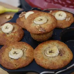 Frisch gebackene Bananen Nuss Muffins, garniert mit Bananenscheiben und Walnüssen, liegen in einer Muffinform.
