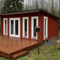 Rött attefallshus med altan i skogsglänta. Perfekt för dig som vill bygga attefallshus och njuta av naturen.