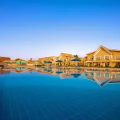 Basen hotelowy w Pickalbatros Sea World Marsa Alam z odbijającymi się w wodzie budynkami i palmami.