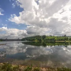 Stausee mit imposanter Staumauer, gespiegelt im ruhigen Wasser. Ein idyllischer Anblick, seen in NRW.