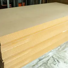 Pile de panneaux de contreplaqué ou aggloméré, prêts à être utilisés pour des projets de construction ou de décoration.