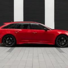 Czerwone Audi RS6 Avant na czarnym tle z białymi pasami. Zastanawiasz się nad audi rs6 cena?
