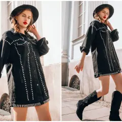 Kobieta w kapeluszu i czarnej kurtce z ćwiekami, styl grunge damski. Długie buty kowbojki dopełniają stylizację.