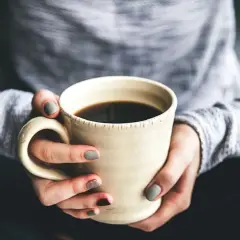 Dłonie trzymają kubek z kawą. Chcesz wiedzieć, jak zrobić kawę rozpuszczalną Nescafé? To proste!