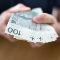 Dłonie trzymają stos banknotów 100 zł. To może być początek drogi do finansowej stabilności, jak kasa stefczyka konsolidacja.