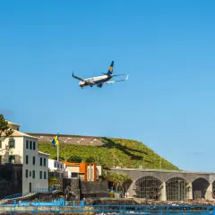 Samolot Ryanair ląduje na lotnisku na Maderze, nad budynkami i basenem z delfinem.