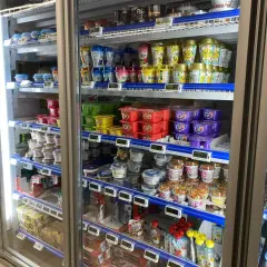 W lodówce w Norwegii widać jogurty i desery. Ceny w sklepach są widoczne na etykietach, np. 27,90 za jogurt.